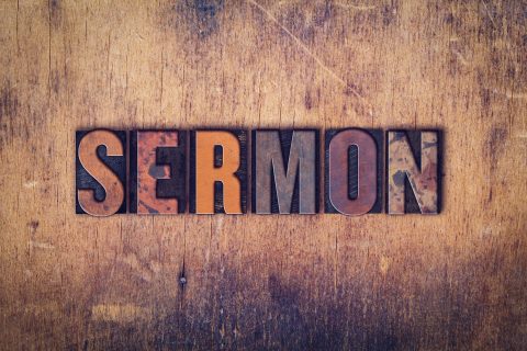 The word "Sermon" written in dirty vintage letterpress type on a aged wooden background.